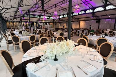 Terrasse extérieure avec tables, chaises, parasol, plantes et vue sur un bâtiment vitré sous un ciel dégagé.