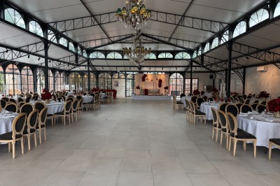Terrasse extérieure avec tables, chaises, parasol, plantes et vue sur un bâtiment vitré sous un ciel dégagé.