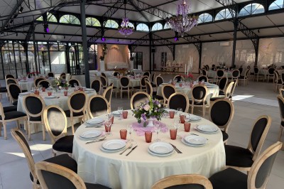 Terrasse extérieure avec tables, chaises, parasol, plantes et vue sur un bâtiment vitré sous un ciel dégagé.