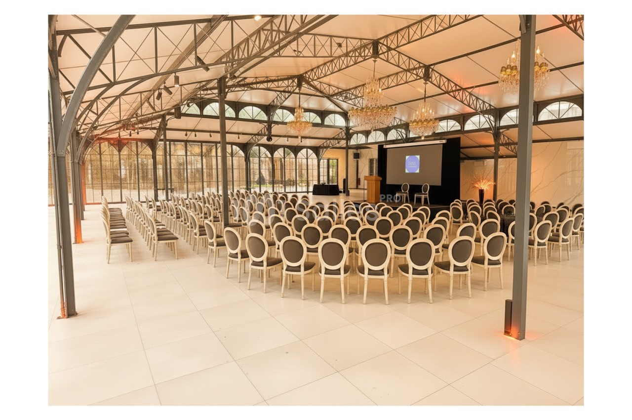 Salle de conférence lumineuse avec rangées de chaises alignées face à un écran et une estrade.