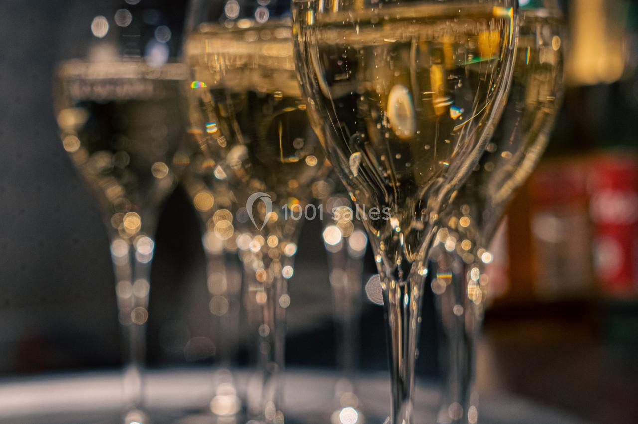 Six flûtes de champagne alignées sur un plateau dans un environnement faiblement éclairé.