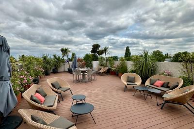 Salon mansardé avec canapé gris, fauteuils, tables d'appoint et éclairage naturel provenant d'une fenêtre inclinée.