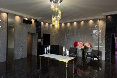 Salon mansardé avec canapé gris, fauteuils, tables d'appoint et éclairage naturel provenant d'une fenêtre inclinée.