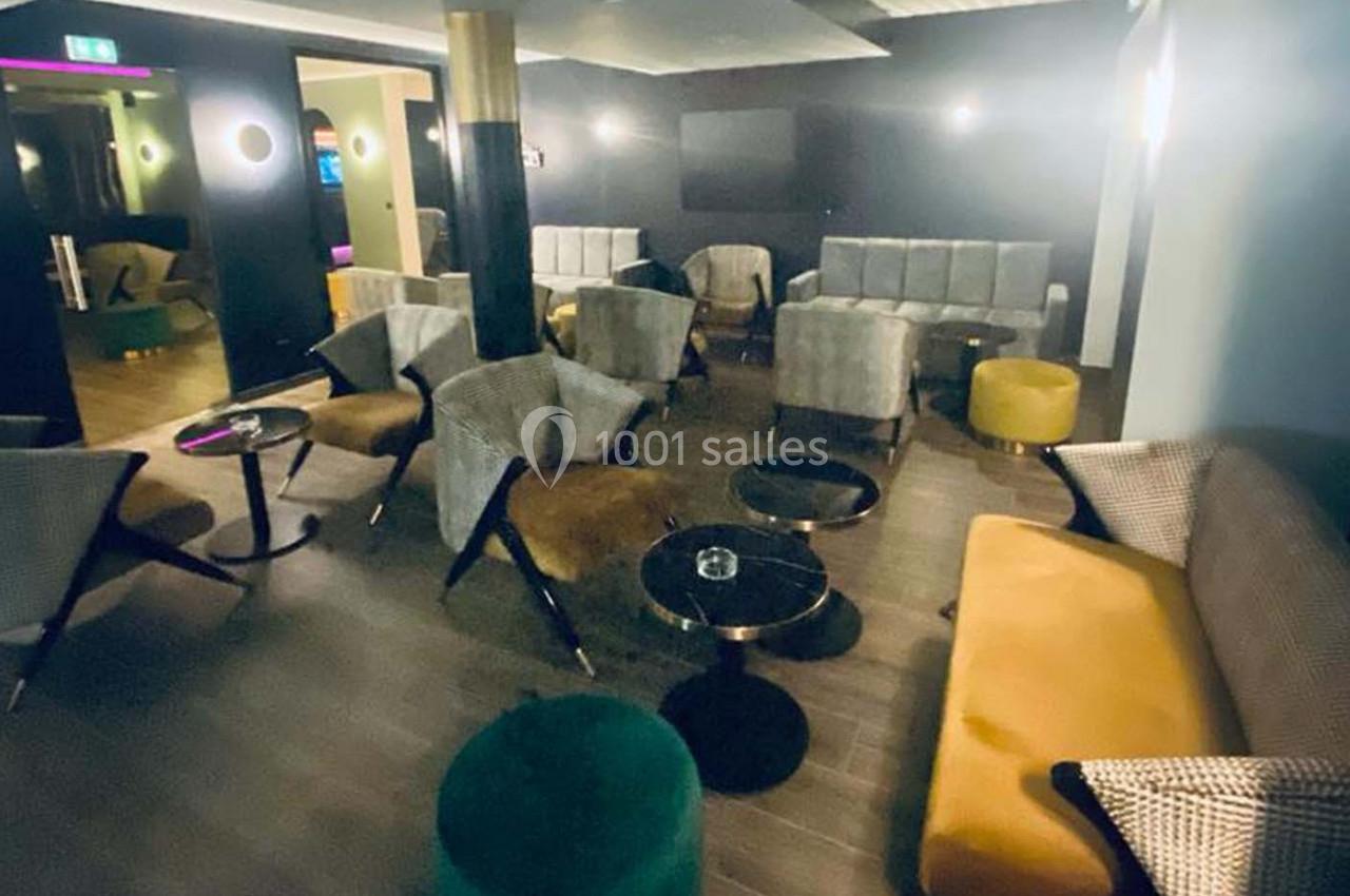 Salle de détente moderne avec fauteuils, canapés, tables basses et éclairage tamisé.