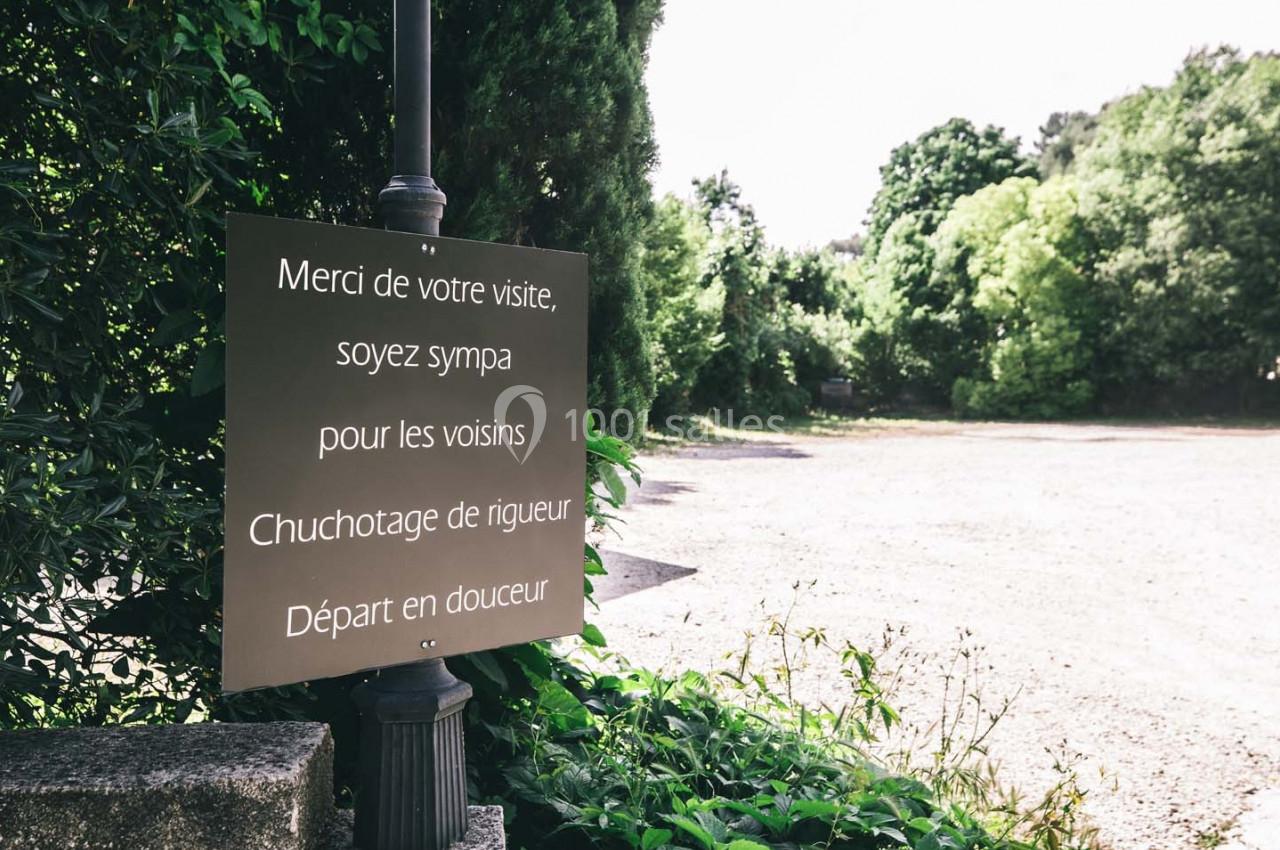 Panneau indiquant des consignes de respect et de discrétion dans un espace extérieur verdoyant.