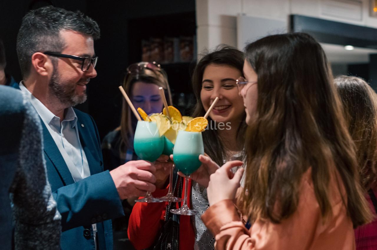 Des personnes trinquent avec des cocktails colorés dans un cadre convivial.