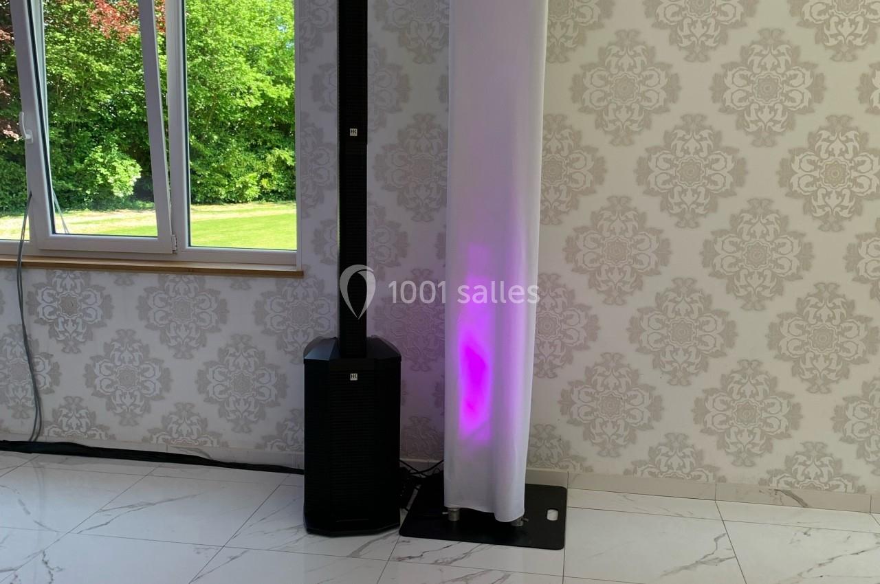 Système de sonorisation et éclairage avec colonne lumineuse et projecteur LED, installé dans une pièce lumineuse.