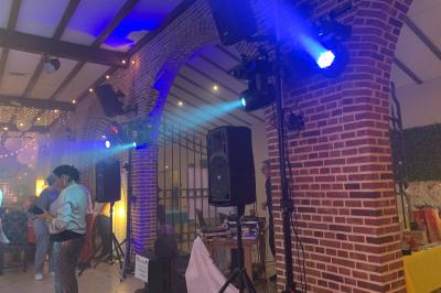 Miniature Show Spectacle #24 Façade d'un bâtiment en briques avec grandes fenêtres, porte ouverte et équipements audio installés à l'extérieur.