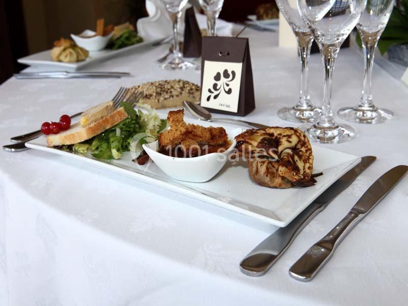 Assiette gastronomique avec foie gras, pain, salade et accompagnements, servie sur une table dressée élégamment.