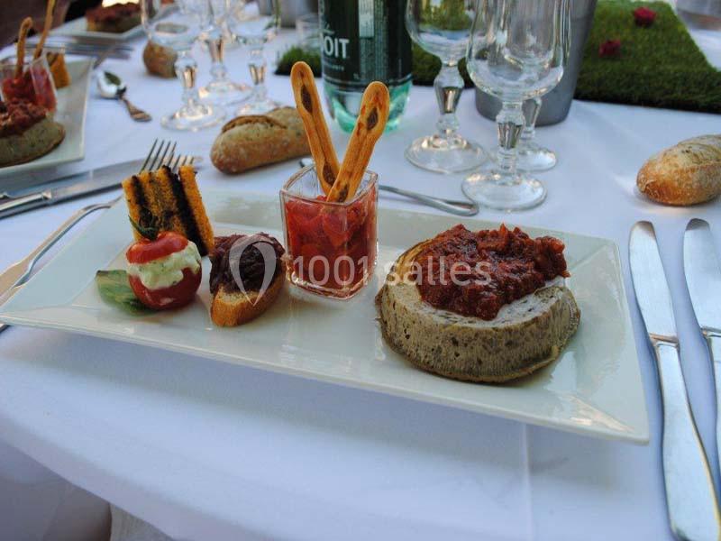 Assiette gastronomique avec champignon farci, verrine de sauce, tomate garnie et toasts, sur une table dressée.
