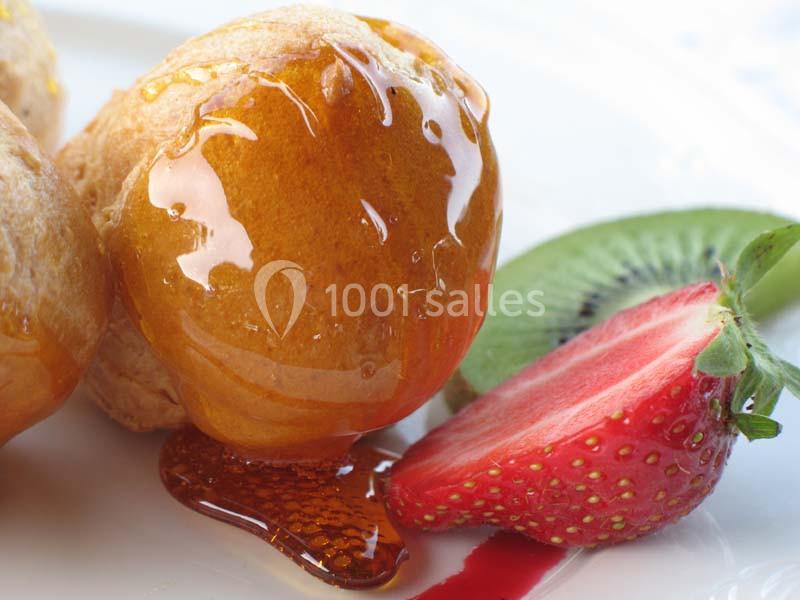 Choux glacés au caramel accompagnés de tranches de fraise et de kiwi sur une assiette blanche.