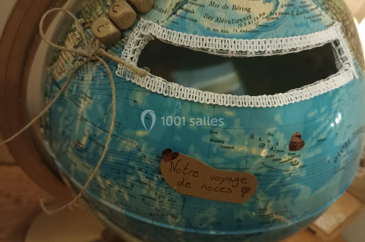 Globe terrestre transformé en urne avec une fente décorée et une étiquette indiquant ’Notre voyage de noces’.