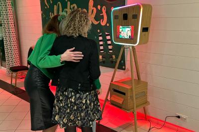 Deux femmes regardent un écran d'une borne photo rétro dans un espace décoré pour la Saint-Patrick.