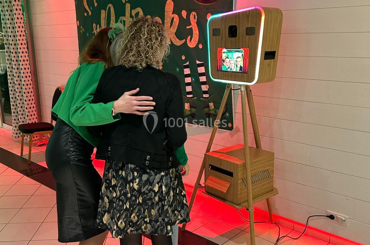 Deux femmes regardent un écran d'une borne photo rétro dans un espace décoré pour la Saint-Patrick.