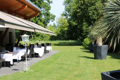 Miniature Terrasse coté jardin Salle de restaurant lumineuse avec tables dressées, nappes blanches, chaises noires et grandes fenêtres donnant sur l…