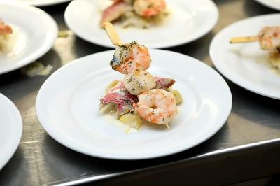 Miniature Traiteur Gagny (Seine-Saint-Denis) - J&J Traiteur Événementiel #4 Des personnes préparent et disposent des desserts sur des assiettes alignées dans une cuisine professionnelle.