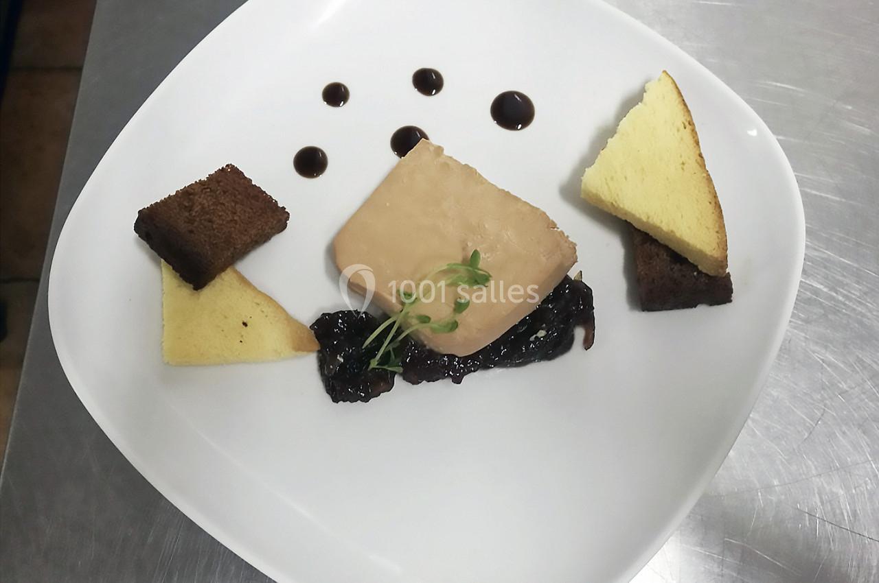 Assiette contenant une tranche de foie gras, des toasts triangulaires, une compotée et des gouttes de sauce balsamique.