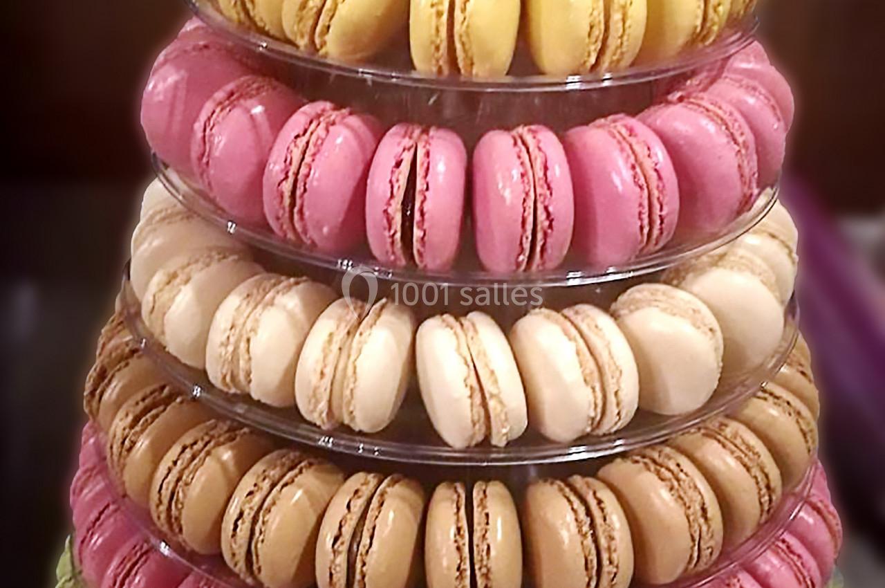 Tour de macarons colorés disposés sur plusieurs étages en présentoir transparent.
