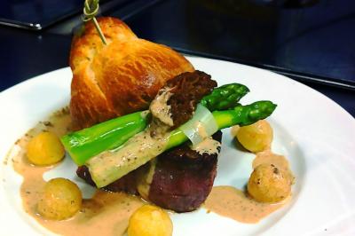 Des personnes préparent et dressent des assiettes avec des desserts dans une cuisine professionnelle.