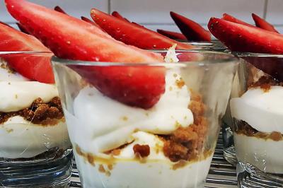 Des personnes préparent et dressent des assiettes avec des desserts dans une cuisine professionnelle.