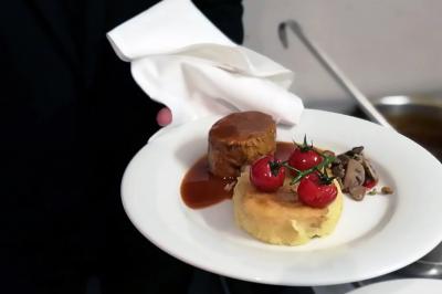 Des personnes préparent et dressent des assiettes avec des desserts dans une cuisine professionnelle.