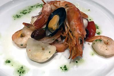 Des personnes préparent et dressent des assiettes avec des desserts dans une cuisine professionnelle.