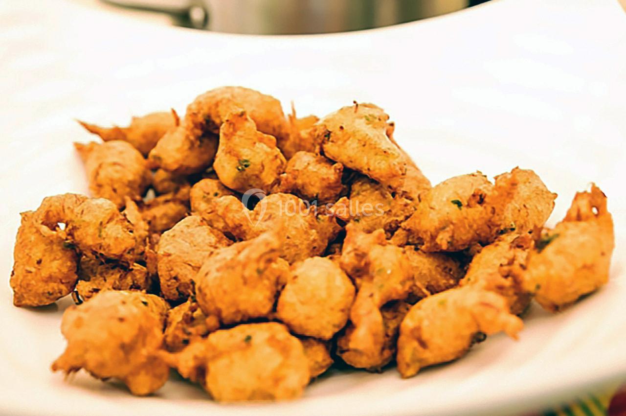 Assortiment de beignets dorés servis sur une assiette blanche.