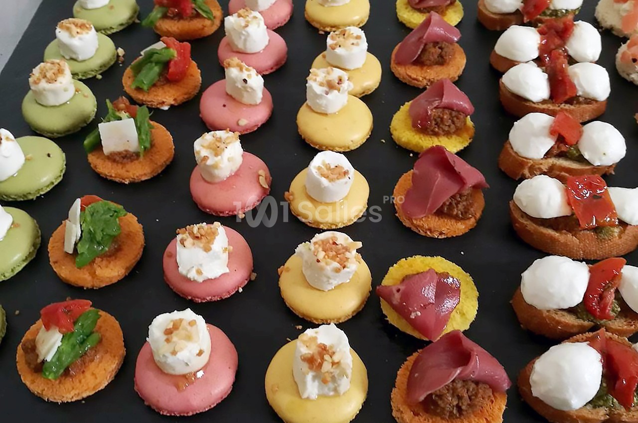 Plateau de bouchées apéritives colorées, composées de macarons salés garnis de fromage, légumes et charcuterie.