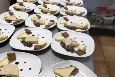 Des personnes préparent et dressent des assiettes avec des desserts dans une cuisine professionnelle.