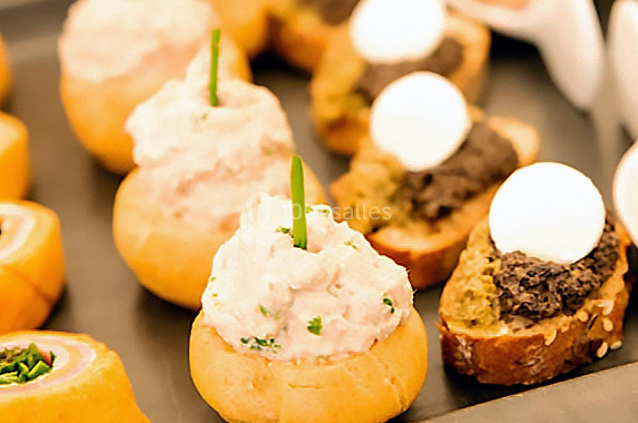 Assortiment de bouchées apéritives comprenant des choux garnis de mousse et des toasts avec tapenade et œufs de caille.