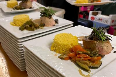 Des personnes préparent et dressent des assiettes avec des desserts dans une cuisine professionnelle.