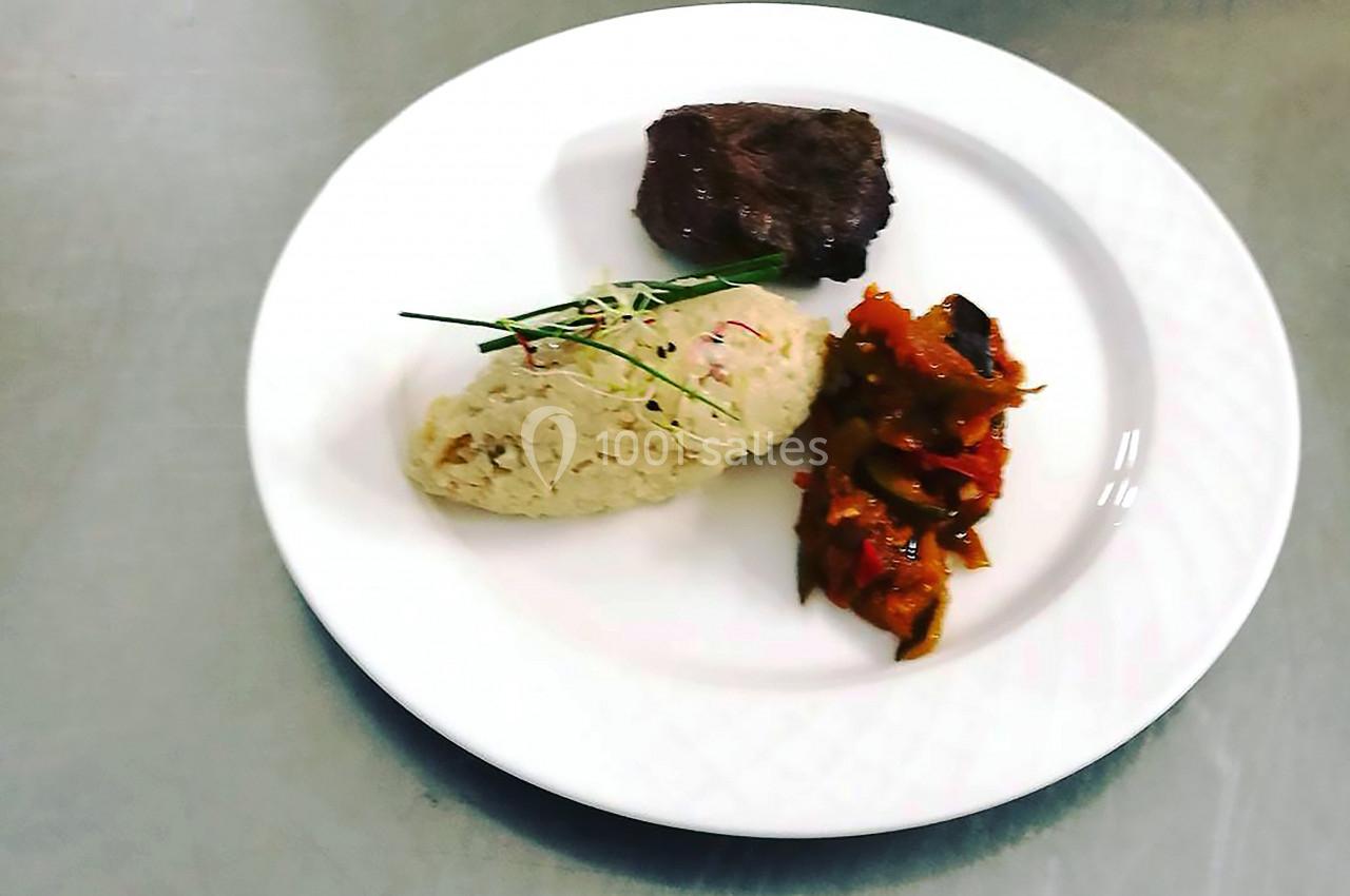 Assiette contenant un morceau de viande, un risotto garni de ciboulette et une portion de légumes cuisinés.