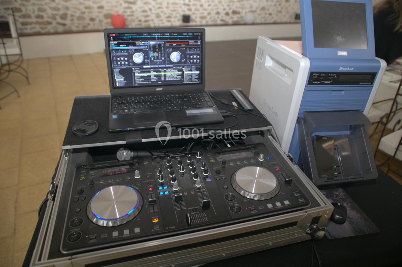 Table de mixage DJ avec ordinateur portable affichant un logiciel de mixage, installée sur une table dans un espace…