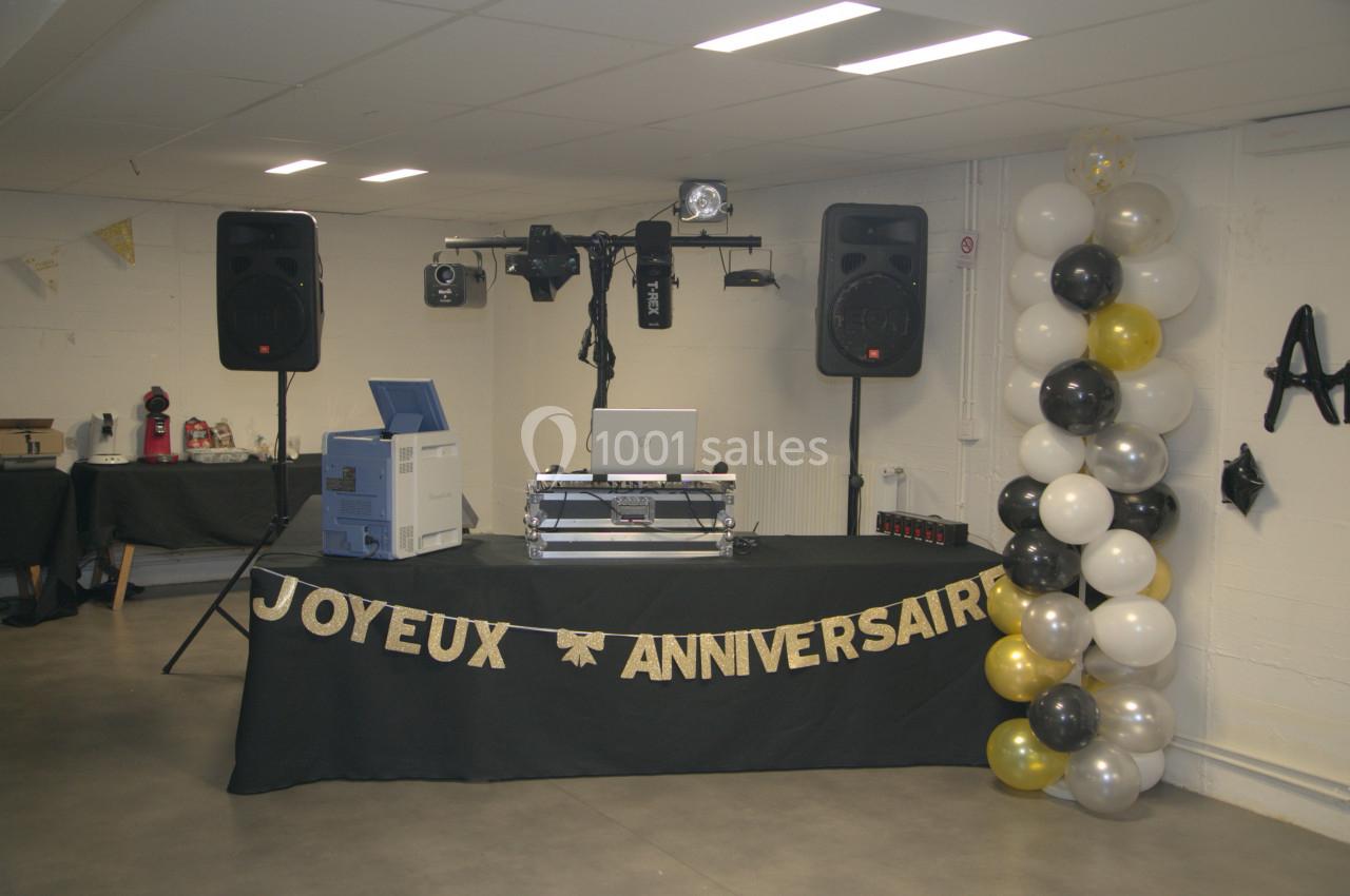 Table de DJ décorée pour un anniversaire, avec guirlande ’Joyeux Anniversaire’, ballons et matériel audio.