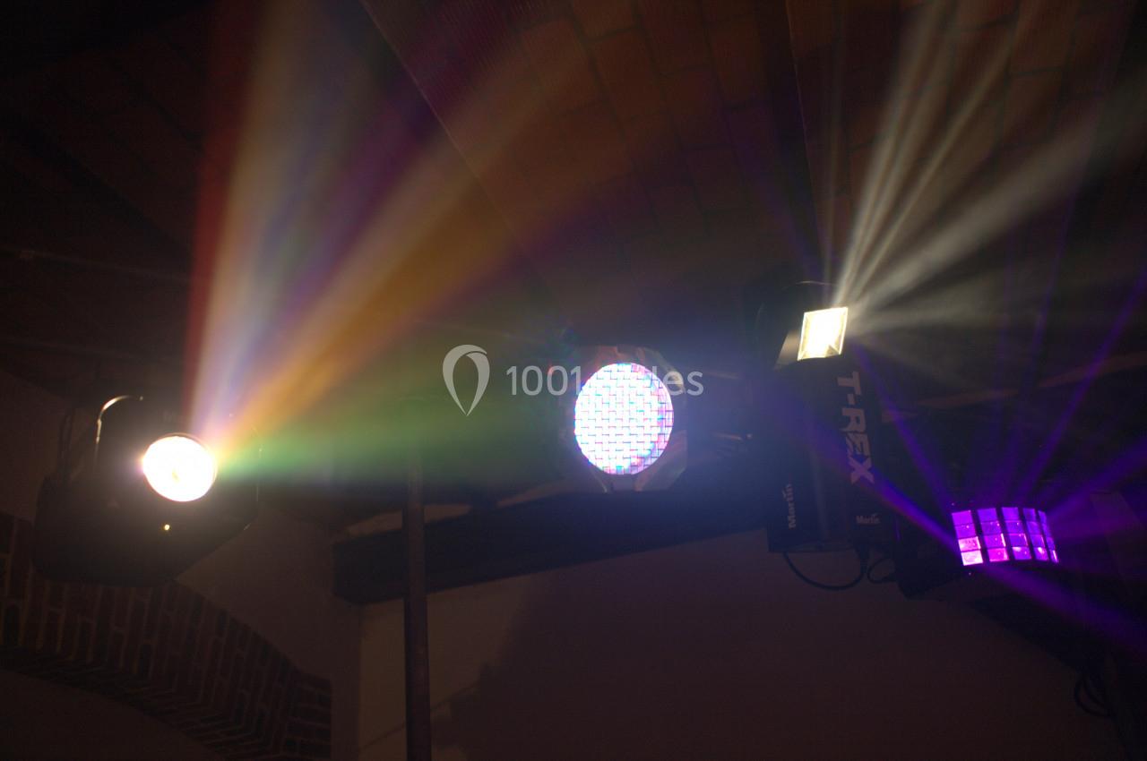Éclairage de scène avec projecteurs diffusant des faisceaux lumineux colorés dans un espace intérieur sombre.