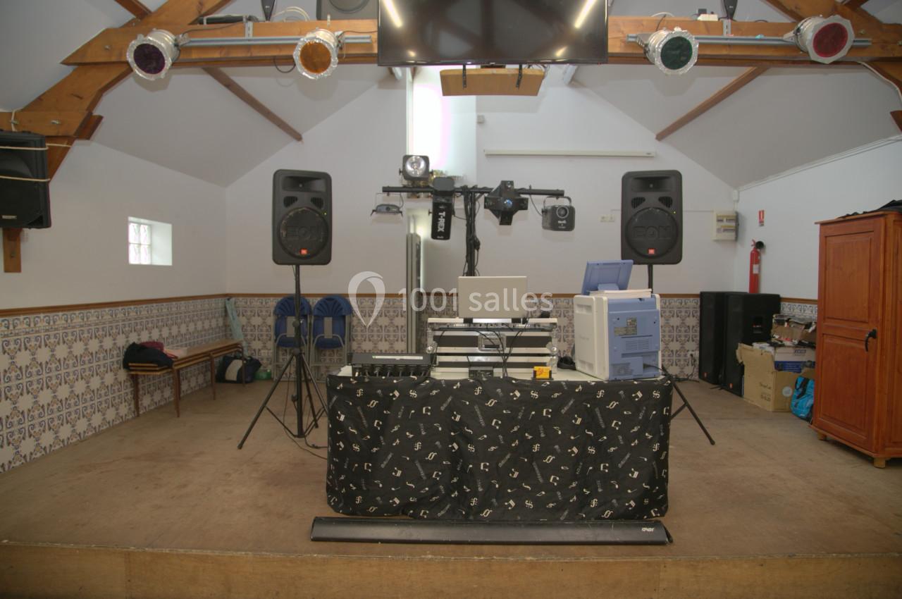 Matériel de sonorisation et éclairage installé dans une salle avec plafond en bois et murs décorés de carreaux.