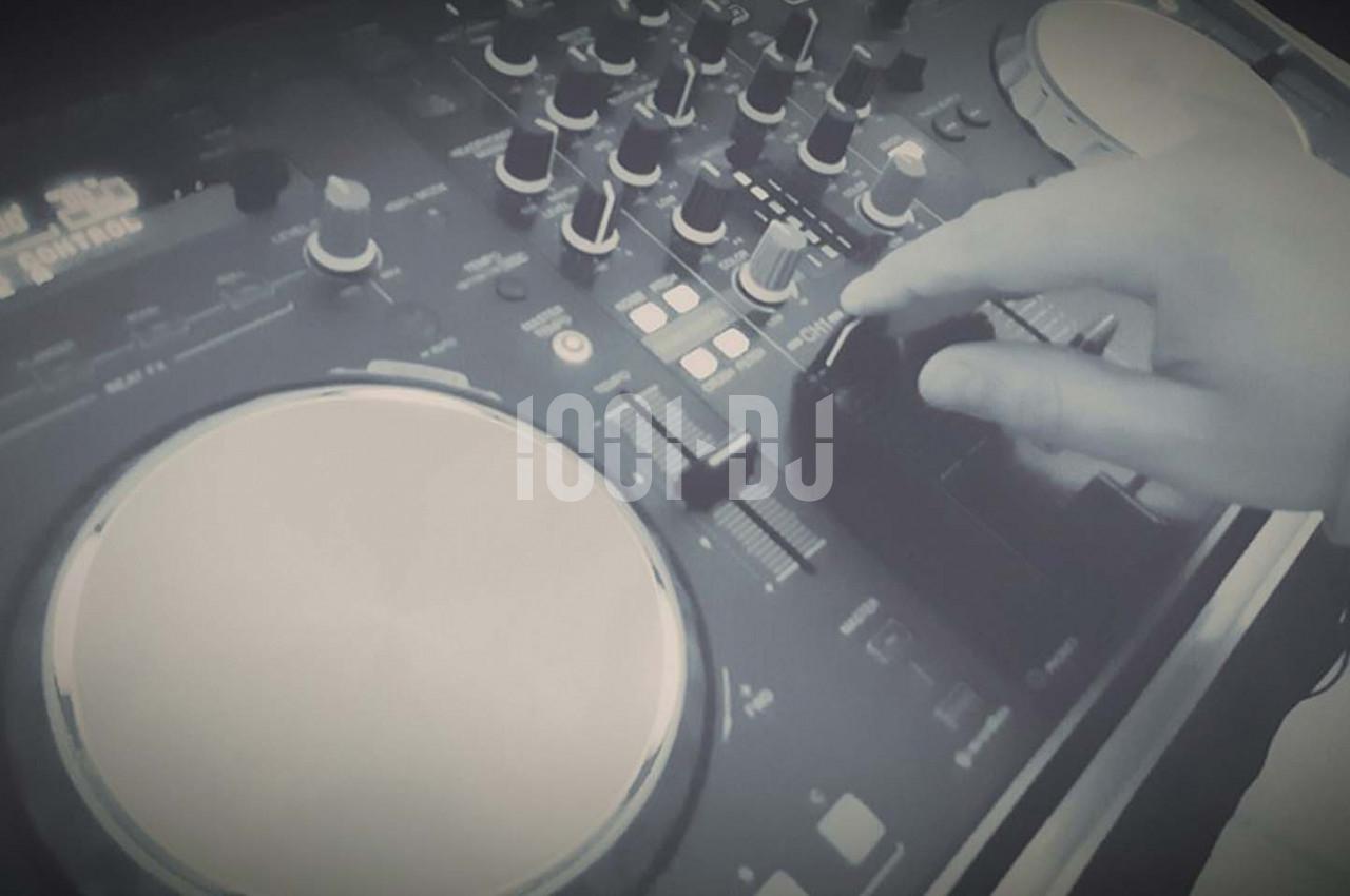 Main ajustant un bouton sur une table de mixage DJ avec des platines et des commandes visibles.