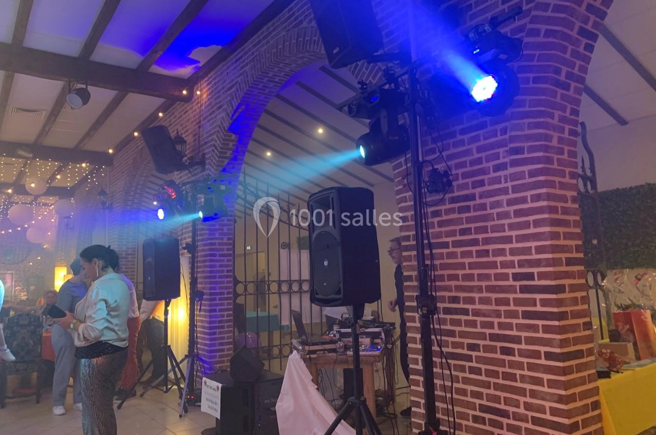 Salle de réception avec éclairage coloré, enceintes et équipements de sonorisation, ambiance festive en intérieur.
