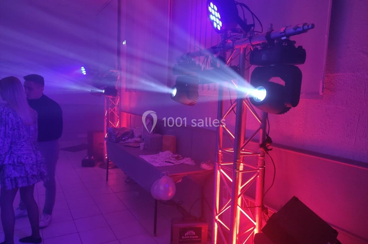 Éclairage de scène avec projecteurs LED colorés et table en arrière-plan dans une salle de réception.
