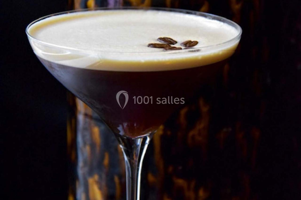Verre à cocktail rempli d'un espresso martini, surmonté d'une mousse crémeuse et décoré de grains de café.