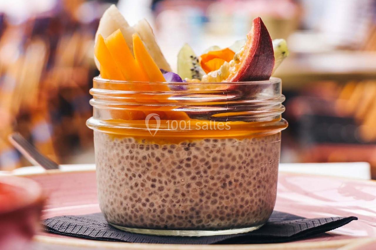 Dessert aux graines de chia dans un bocal, garni de fruits frais colorés comme mangue, kiwi et pêche.