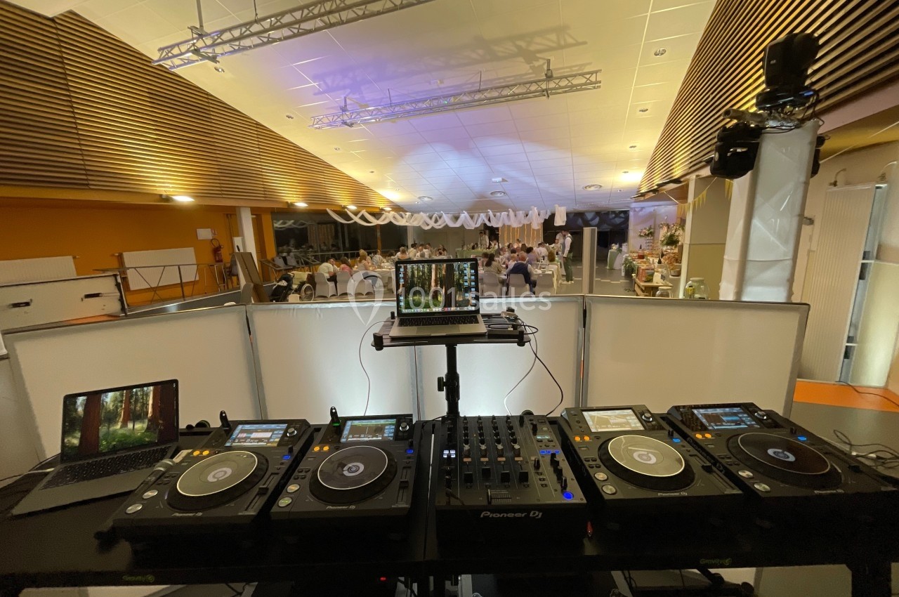 Équipement de DJ avec platines et ordinateur installé dans une salle de réception éclairée.