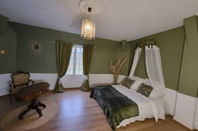 Salon ancien avec parquet en bois, mobilier classique, cheminée, miroir, coiffeuse et grande fenêtre avec rideaux roses.