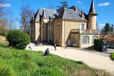 Salon ancien avec parquet en bois, mobilier classique, cheminée, miroir, coiffeuse et grande fenêtre avec rideaux roses.