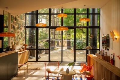 Miniature Location salle Lacanau (Gironde) - La Baignoire #14 Chambre lumineuse avec lit double, balcon donnant sur un espace arboré, rideaux rouges et lampe de chevet allumée.