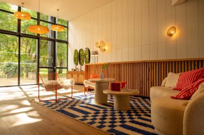 Miniature Location salle Lacanau (Gironde) - La Baignoire #13 Chambre lumineuse avec lit double, balcon donnant sur un espace arboré, rideaux rouges et lampe de chevet allumée.