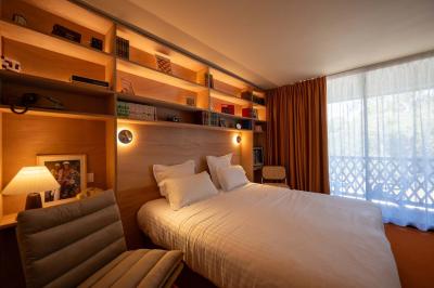 Miniature Location salle Lacanau (Gironde) - La Baignoire #24 Chambre lumineuse avec lit double, balcon donnant sur un espace arboré, rideaux rouges et lampe de chevet allumée.