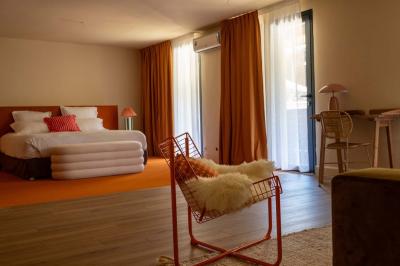 Miniature Location salle Lacanau (Gironde) - La Baignoire #27 Chambre lumineuse avec lit double, balcon donnant sur un espace arboré, rideaux rouges et lampe de chevet allumée.