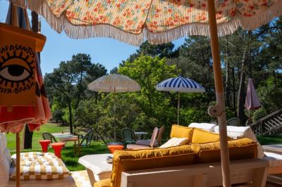 Miniature Location salle Lacanau (Gironde) - La Baignoire #3 Chambre lumineuse avec lit double, balcon donnant sur un espace arboré, rideaux rouges et lampe de chevet allumée.