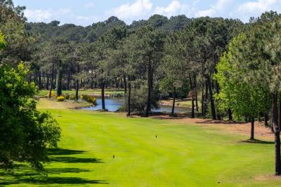 Miniature Location salle Lacanau (Gironde) - La Baignoire #4 Chambre lumineuse avec lit double, balcon donnant sur un espace arboré, rideaux rouges et lampe de chevet allumée.